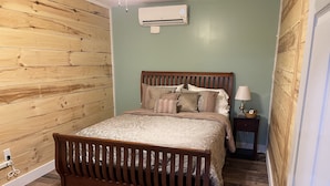 A bedroom with a wooden bed frame, a headboard, and a bedside table with a lamp. - New Near Jamestown Dock - A (Jamestown)