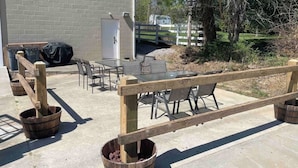 An outdoor patio area with a wooden fence, tables, chairs, and a covered seating area. - New Near Jamestown Dock - A (Jamestown)