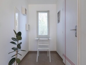A room with a radiator, a window with blinds, a white chair, and a door with a handle. - Elaia Phoebé in the Mediterranean – 14-meter heated pool (TOUROUZELLE 11200)