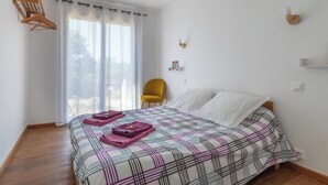 Une chambre à coucher avec un lit, une chaise et une fenêtre avec des rideaux.