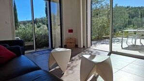 Un soggiorno moderno con un divano, due tavolini e vista su un patio con tavolo e sedie.