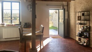 A rustic kitchen with a wooden table and chairs, a radiator, and a window with a view of the outside. - 18th century character gîte in the VAL DE CHAMBORD at the gates of Chambord (Huisseau-sur-Cosson)