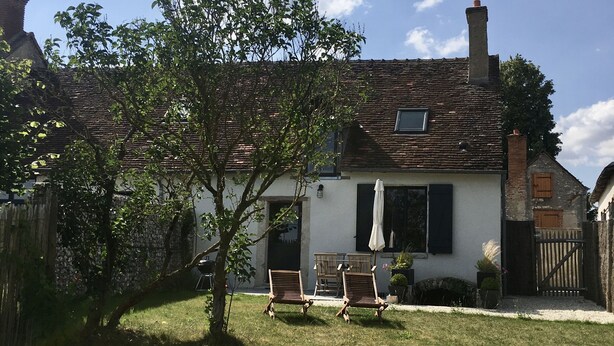 A house with a sloped roof, a small porch, and two wooden chairs in the yard. - 18th century character gîte in the VAL DE CHAMBORD at the gates of Chambord (Huisseau-sur-Cosson)