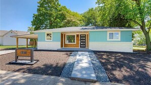 A single-story house with a light blue exterior, a front porch, and a driveway leading to the entrance. - Newly Rennovated Home next to Zoo and Downtown Stadiums (Indianapolis)