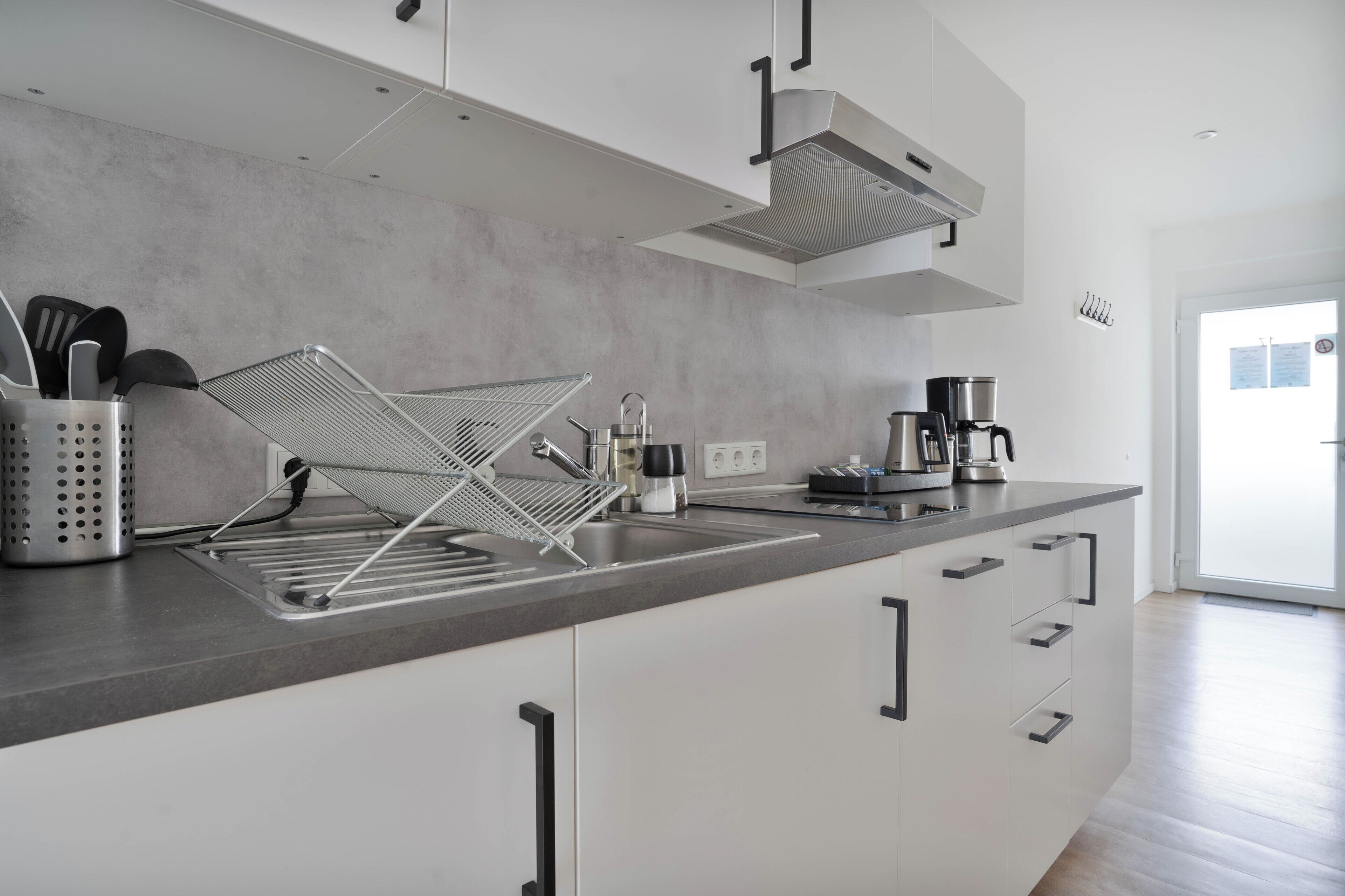 A modern kitchen with a stainless steel sink, a coffee machine, and a kettle.