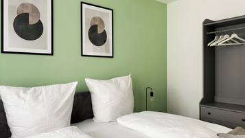 Ein Hotelzimmer mit zwei Betten, einer grünen Wand und zwei abstrakten Kunstwerken.