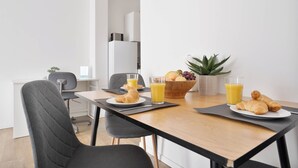 En morgenmadsopstilling med croissanter, appelsinjuice og en skål med frugt på et træbord.