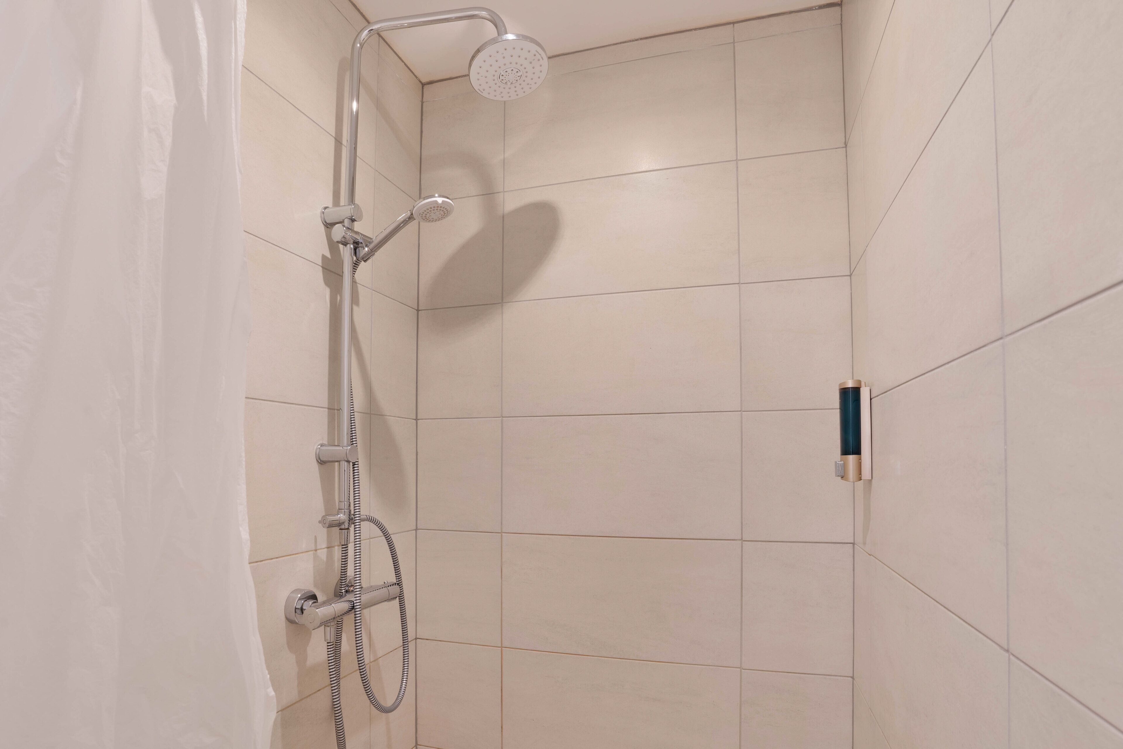 A shower with a handheld showerhead and a wall-mounted faucet.