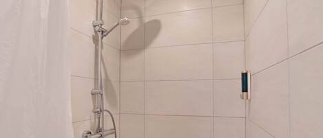 A shower with a handheld showerhead and a wall-mounted faucet.