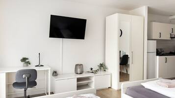 Um quarto moderno com uma cama, uma escrivaninha e uma televisão.