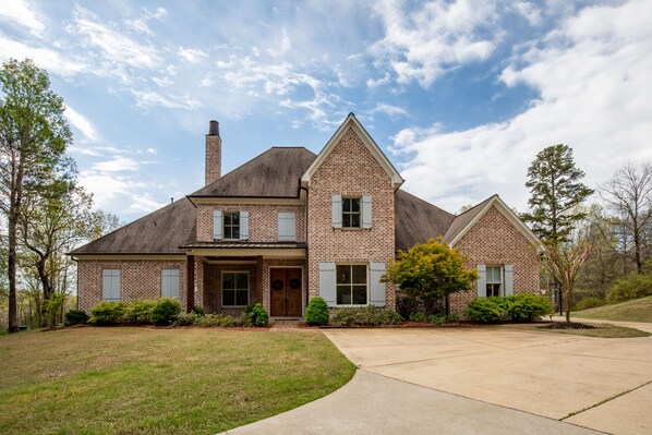 A two-story brick house with a gabled roof, a chimney, and a front porch.