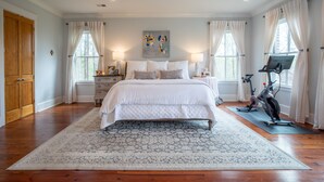 A spacious bedroom with a large bed, exercise bike, and a ceiling fan. - Spacious, serene retreat perfect for Oxford visits<br>New listing!!  (Oxford)