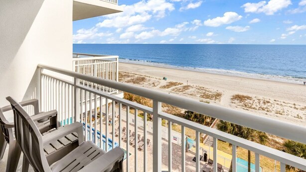 Un balcon avec vue sur la plage et l’océan.