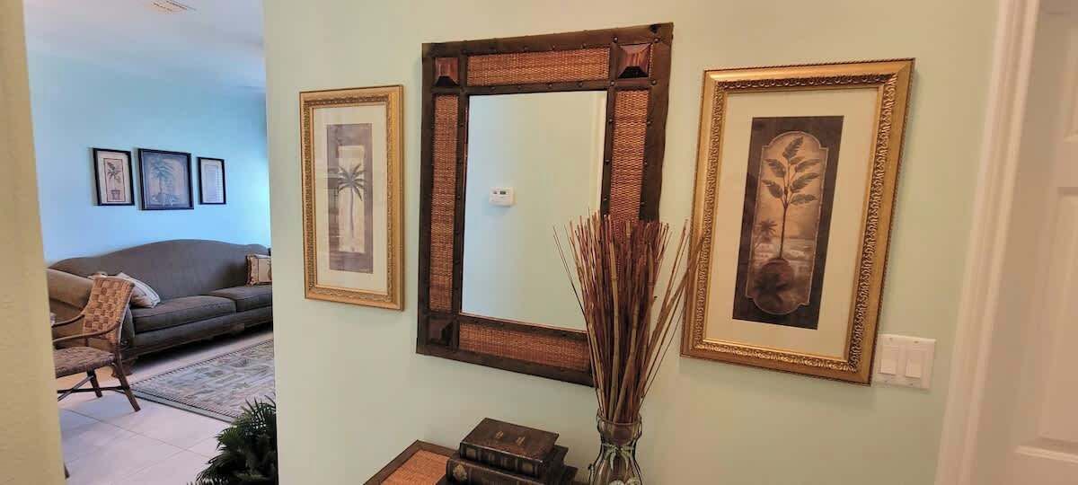 A living room with a sofa, a large mirror, and framed artwork on the wall.