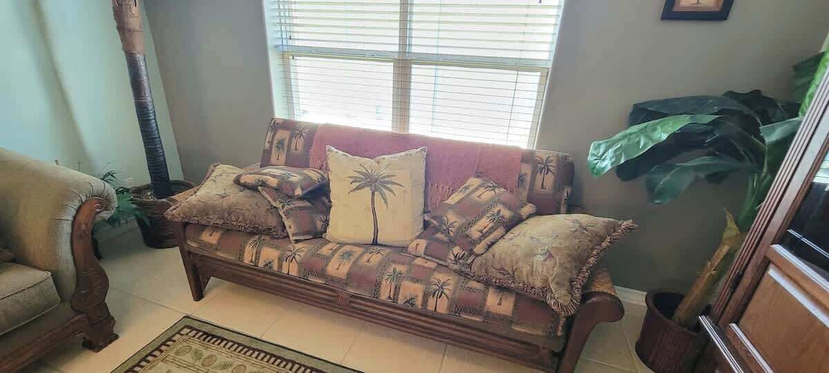 A cozy living room with a patterned sofa, a wooden coffee table, and a large green plant.