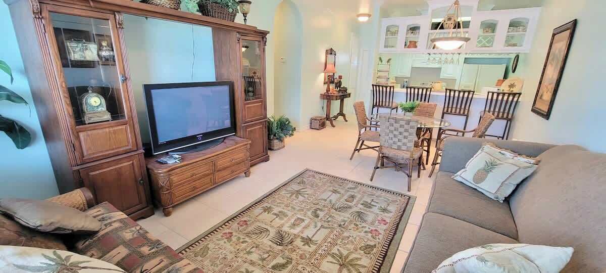Un salon avec un téléviseur, un canapé et un tapis à motifs.