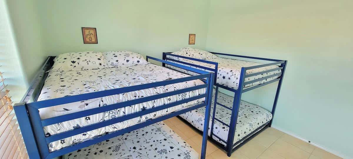 Ein Stockbett mit blauer Metallkonstruktion und blumigem Bettzeug.