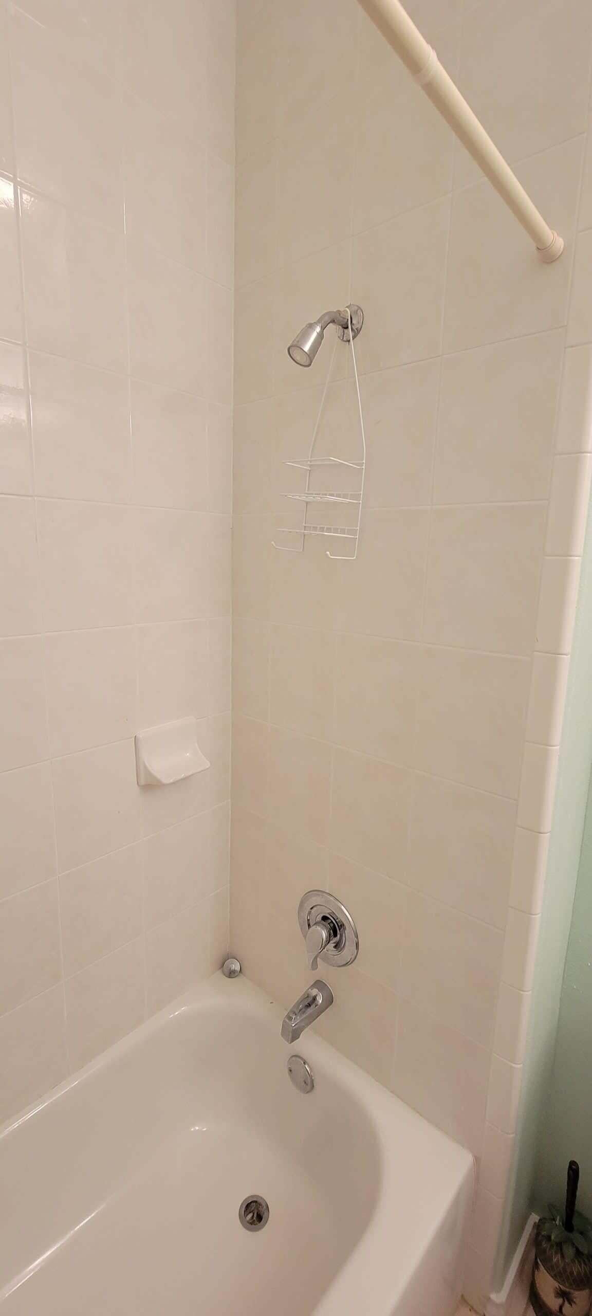A bathroom with a bathtub, a showerhead, and a towel rack.