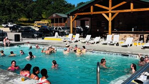 A swimming pool area with lounge chairs and a covered seating area.