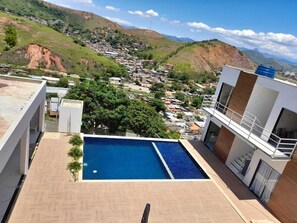 A rooftop pool with a view of a hillside town.
