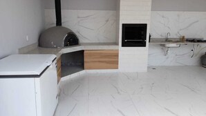 A modern kitchen with a built-in oven, a sink, and a marble backsplash. - Vista Bela (Tres Rios)