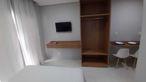 A modern hotel room with a bed, a desk with a chair, a TV mounted on the wall, and a wardrobe. - Vista Bela (Tres Rios)