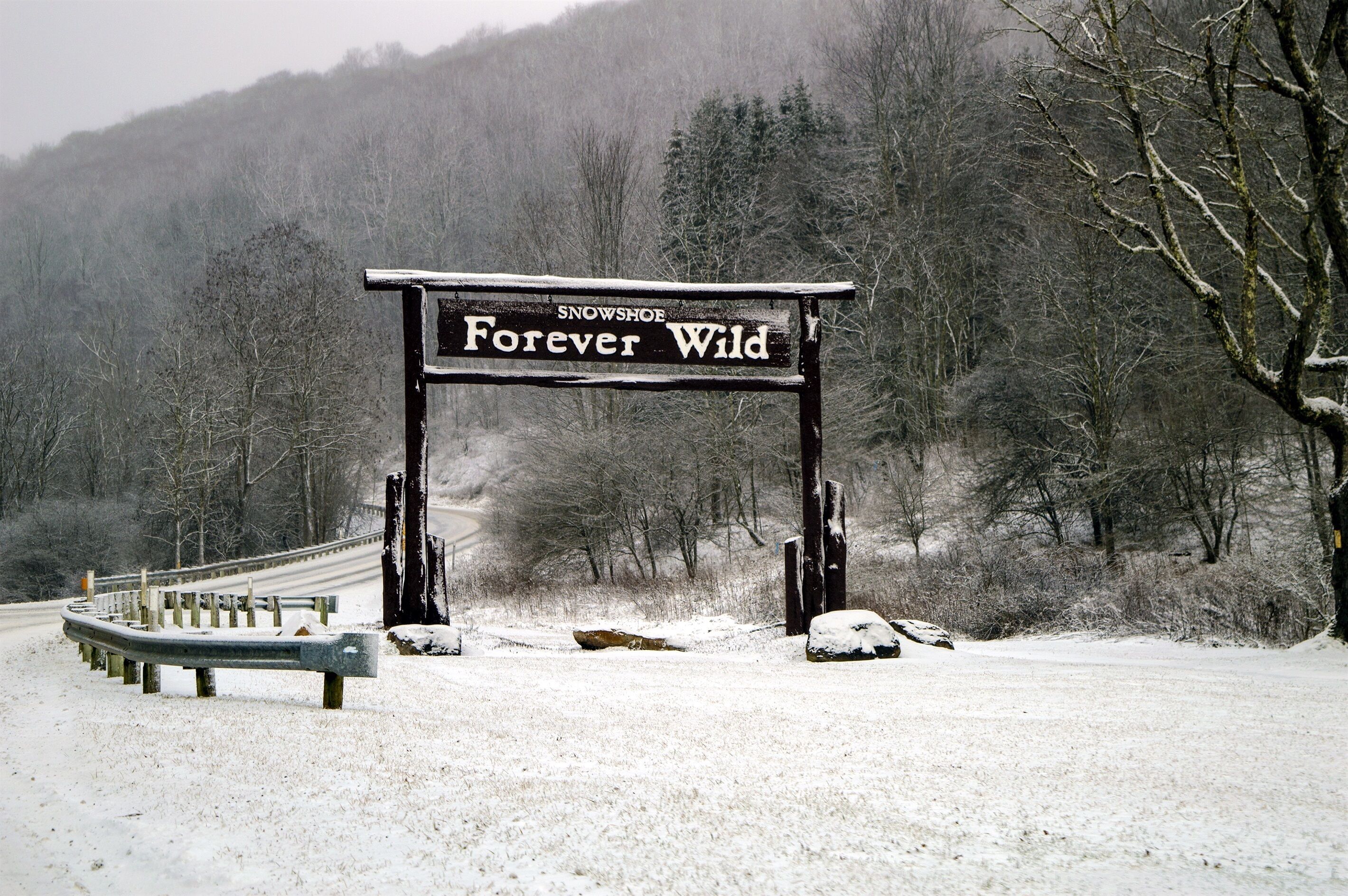 Eine verschneite Straße mit einem Schild, auf dem 'Snowshoe Forever Wild' steht.