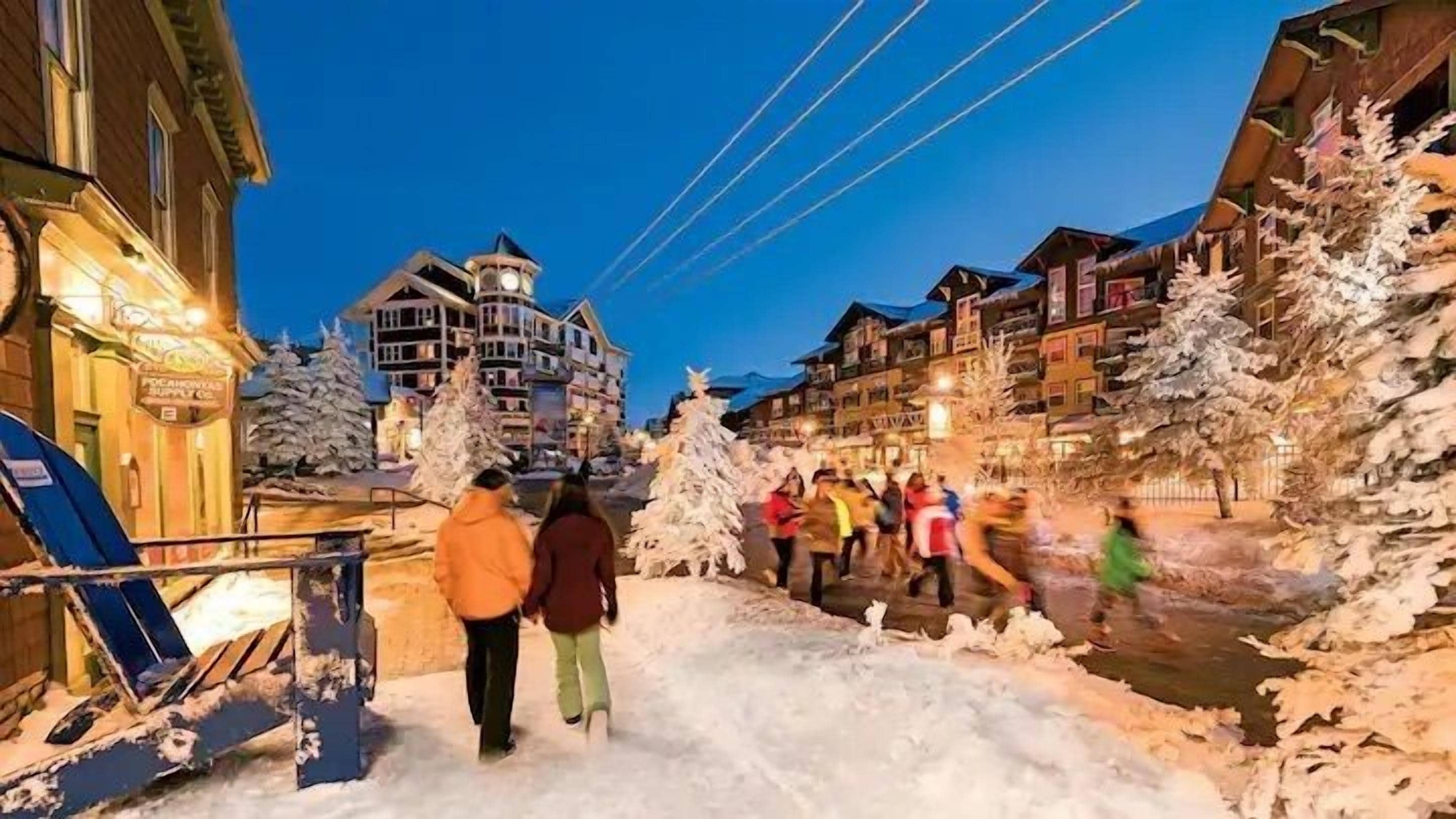 A snow-covered street with buildings and a ski lift.