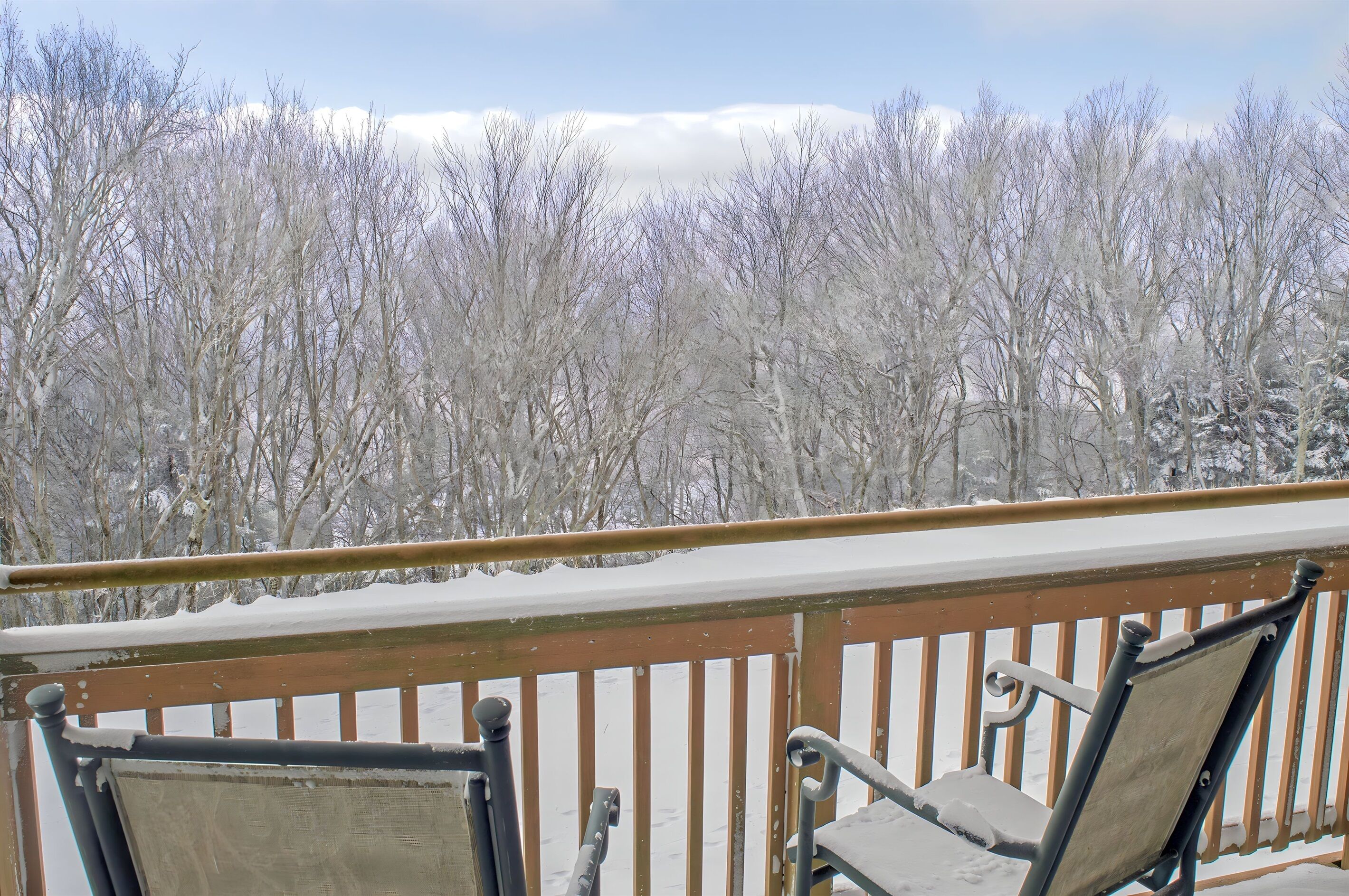 A balcony with a wooden railing and two chairs.
