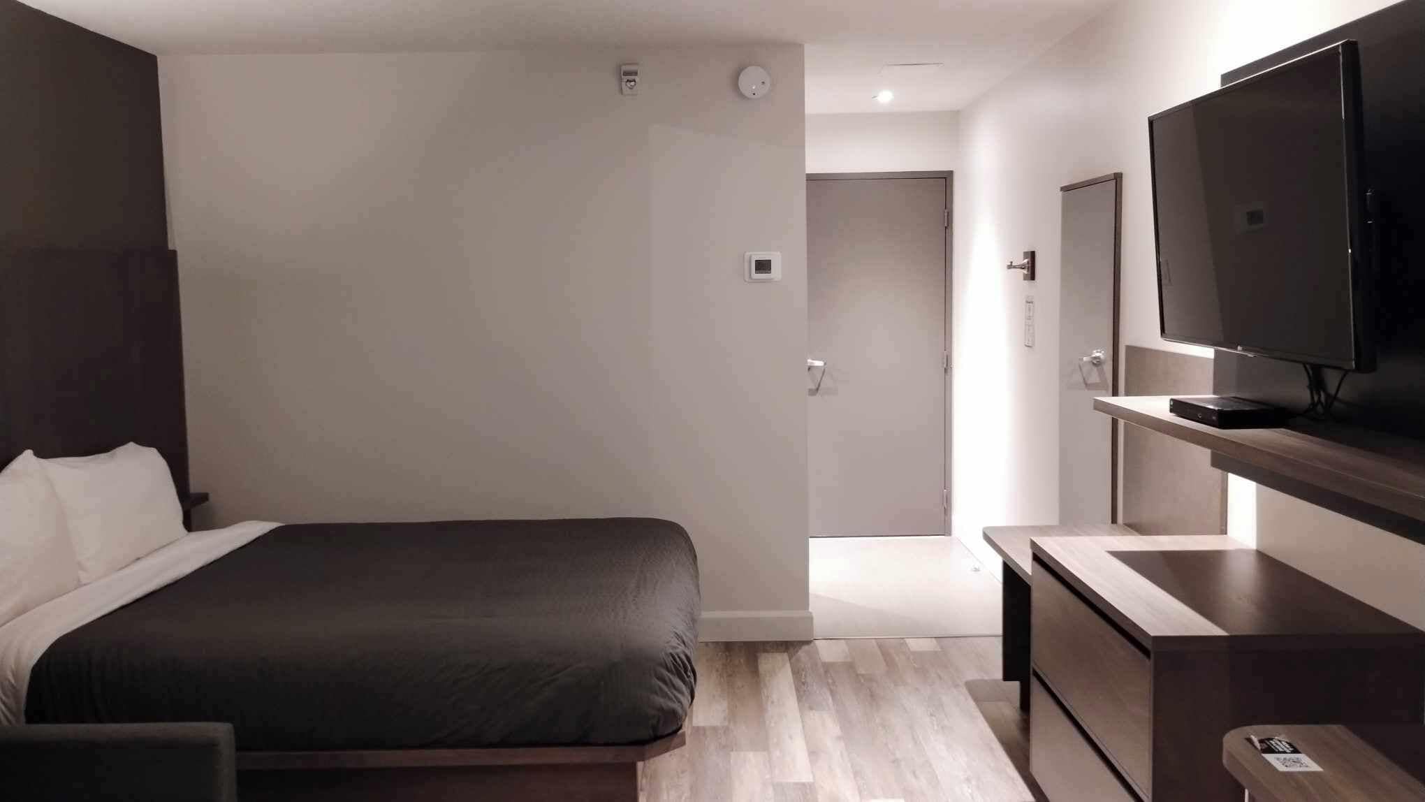 Een moderne hotelkamer met een groot bed, een flatscreen televisie en een houten bureau.