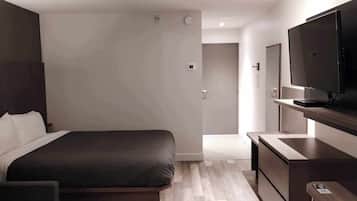 Een moderne hotelkamer met een groot bed, een flatscreen televisie en een houten bureau.
