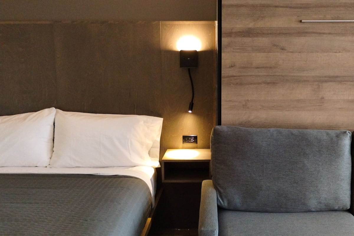 Une chambre d’hôtel avec deux lits, une table de chevet avec une lampe et un mur en bois.