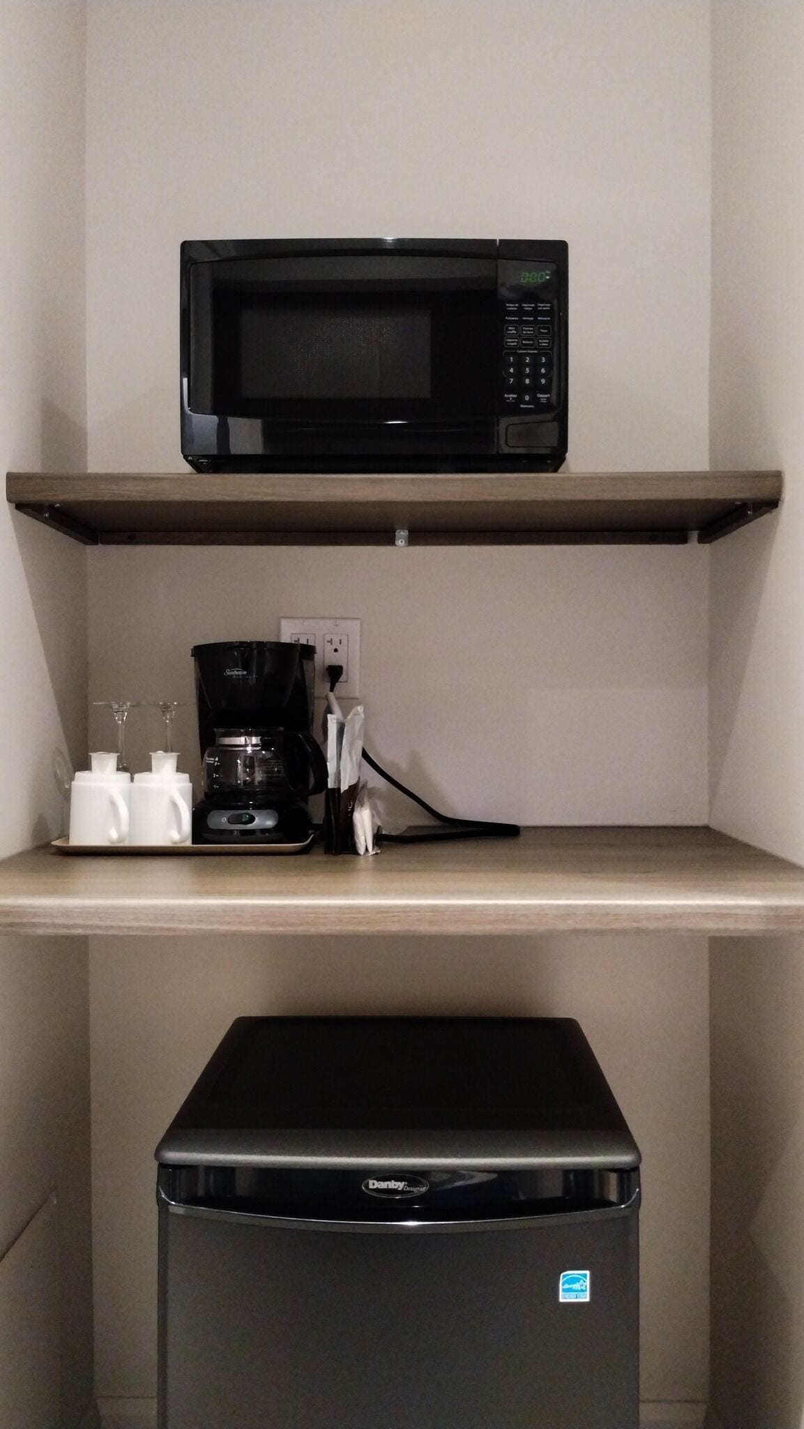 A kitchenette with a microwave on the upper shelf, a coffee maker, and a dishwasher below.