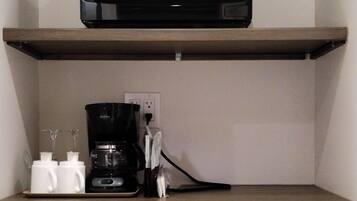 A kitchenette with a microwave on the upper shelf, a coffee maker, and a dishwasher below.