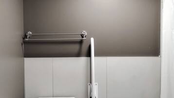 Ein modernes Badezimmer mit Toilette, einer Haltestange und einer Duschvorhang.