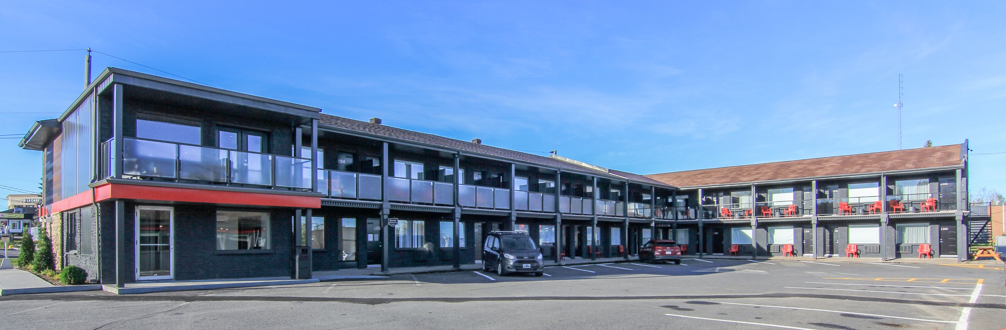 A multi-story hotel with a modern design, featuring a parking lot in front.