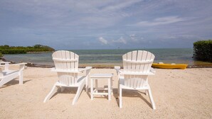 A beach with white Adirondack chairs and a yellow boat on the sand. - 4 Bedroom House in Angler's Reef, Includes 31' Boat Slip. Islamorada, FL (Islamorada)