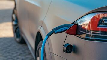 Un coche con un cable de carga conectado a la parte trasera.