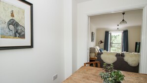 A dining area with a wooden table, a framed artwork, and a potted plant. - 30 Poplar Close (Shrewsbury)