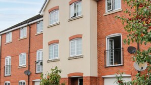 A multi-story residential building with a mix of brick and beige facades, multiple windows, and satellite dishes. - 30 Poplar Close (Shrewsbury)