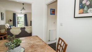A dining area with a wooden table, a potted plant, and a chair. There is a view of a living room with a sofa and a lamp. - 30 Poplar Close (Shrewsbury)