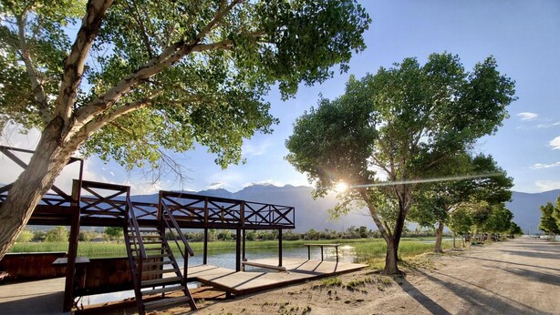 A wooden deck with a metal frame, overlooking a body of water and mountains.
