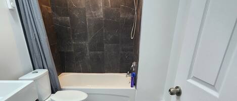 Une salle de bain comprenant des toilettes, une baignoire et une douche.