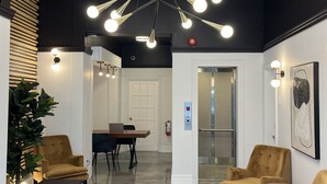 A modern lobby with a high ceiling, a central chandelier, and a seating area with two sofas and a table. - Le Sand & Stone Hôtel (Montreal)