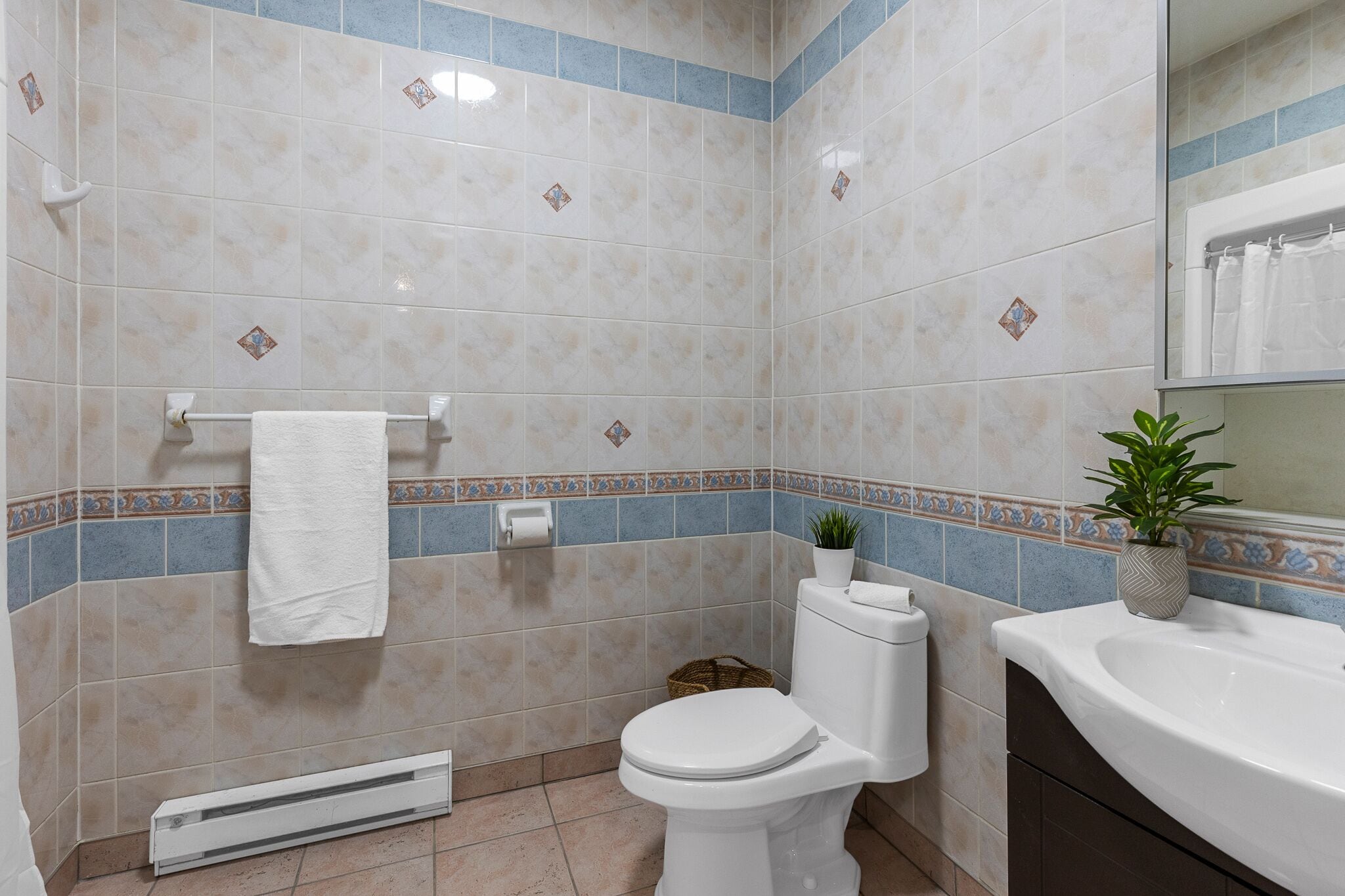 Ein Badezimmer mit Toilette, Waschbecken und einer Topfpflanze.