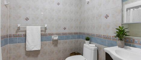 Ein Badezimmer mit Toilette, Waschbecken und einer Topfpflanze.