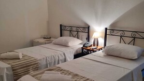 Une chambre d’hôtel avec deux lits simples, une table de chevet avec une lampe et une chaise.
