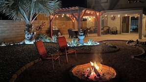 Un patio cubierto con una chimenea, asientos exteriores y una pared decorativa.