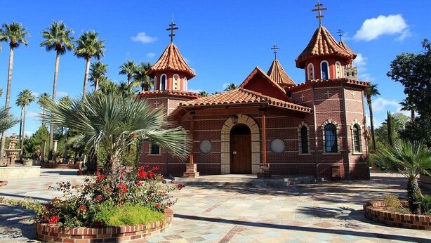 Una iglesia de ladrillo rojo, con varias torres y cruces en la parte superior.