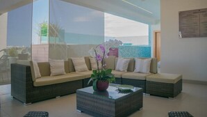 A modern lounge area with a sofa set, a glass coffee table, and a potted orchid.